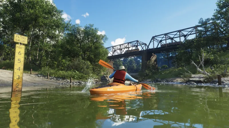 Kajakfahrt im Mount Kalaga National Park. Vorn steht ein Pegelmesser, hinten fährt ein Zug über die Brücke. Bild: Rockstar Games