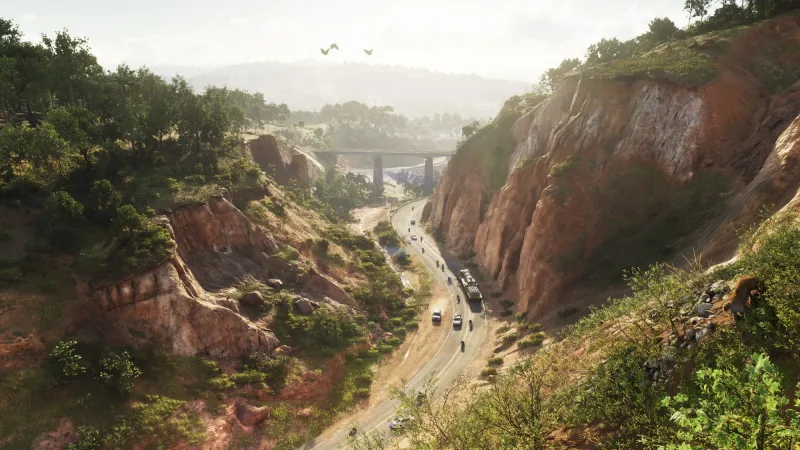 Eine Landstraße schneidet durch eine rote Felsschlucht im Mount Kalaga National Park, dahinter führt eine Brücke über das Tal. Bild: Rockstar Games