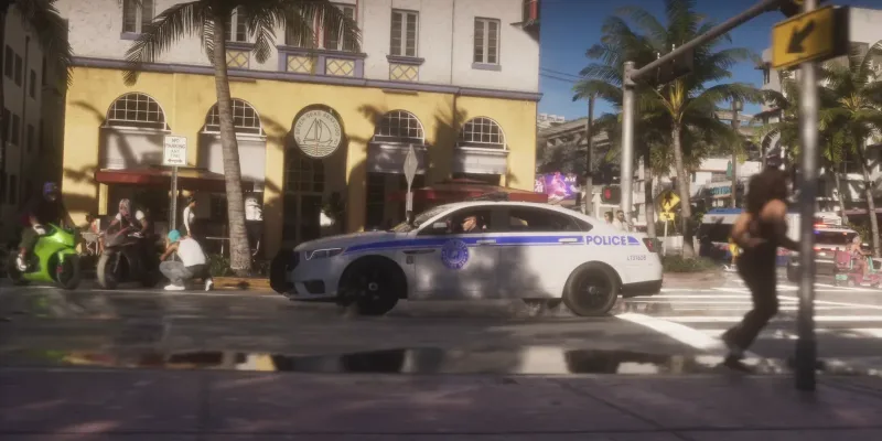 Ein Streifenwagen der Vice City Police Dept. biegt auf einer Straße mit gelbem Gebäude ein, links Motorräder. Bild: Rockstar Games, Launch Trailer
