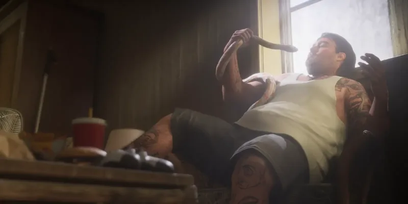Ein tätowierter Mann auf einem Sofa mit einer Schlange am Arm, davor ein Controller und Fast Food. Bild: Rockstar Games, Launch Trailer